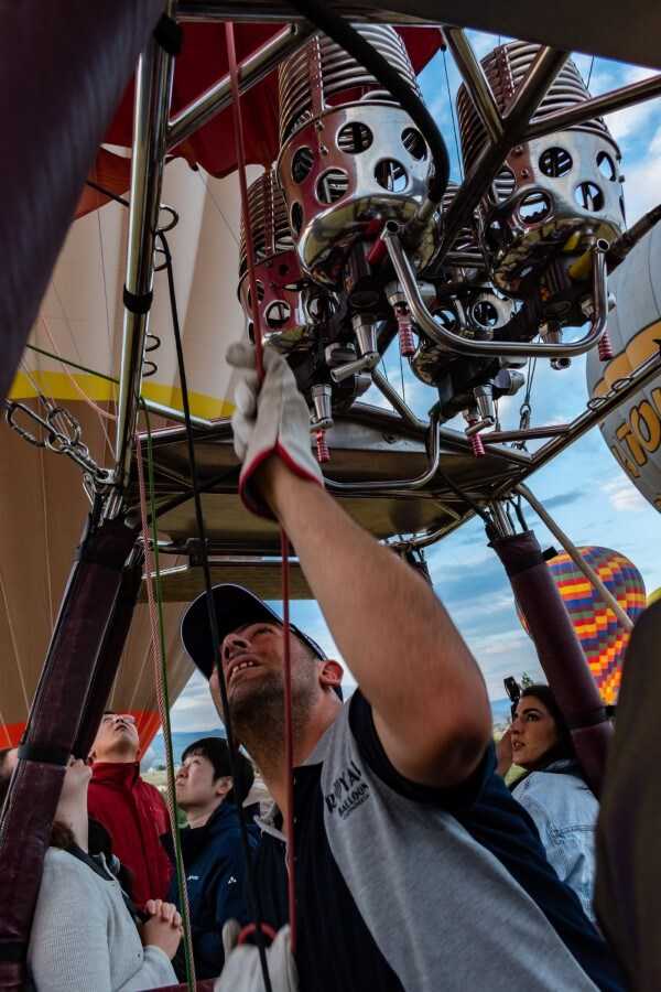 man with grey and blue t-shirt piloting a hot air balloon
