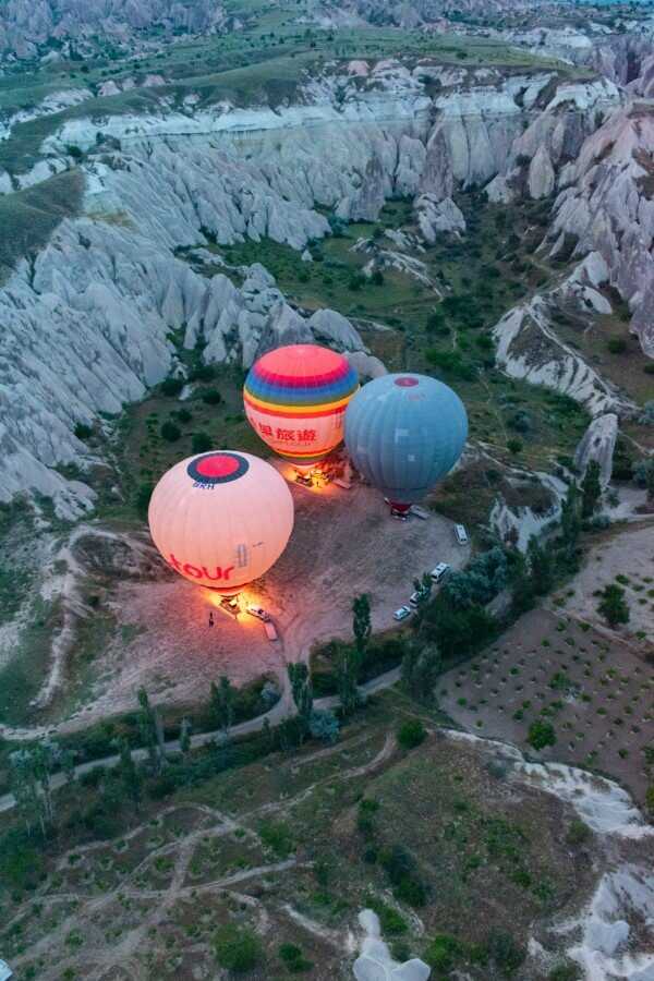 hot air balloons glowing up in the dark before take off