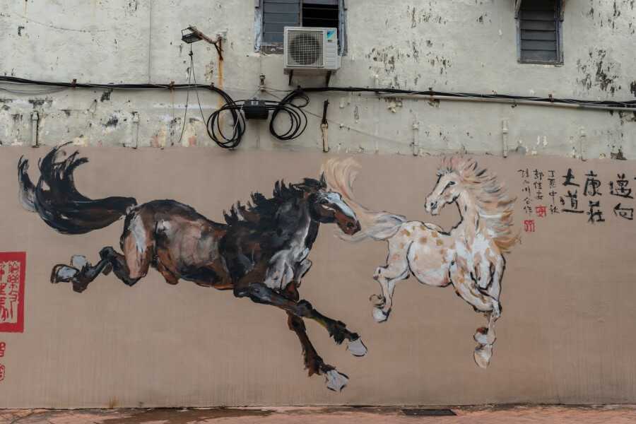 painting of a dark and white horses along the streets of malacca