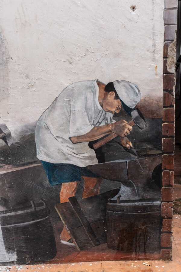 painting of a man forging metal at the well melaka