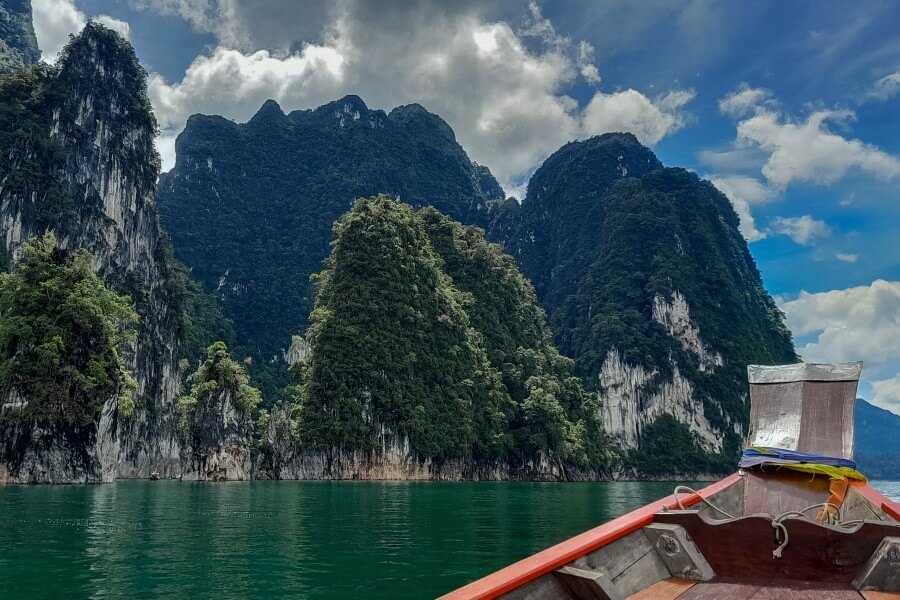view of karst cliffs covered by vegetation from a longtail boat ride on a lake in thailand