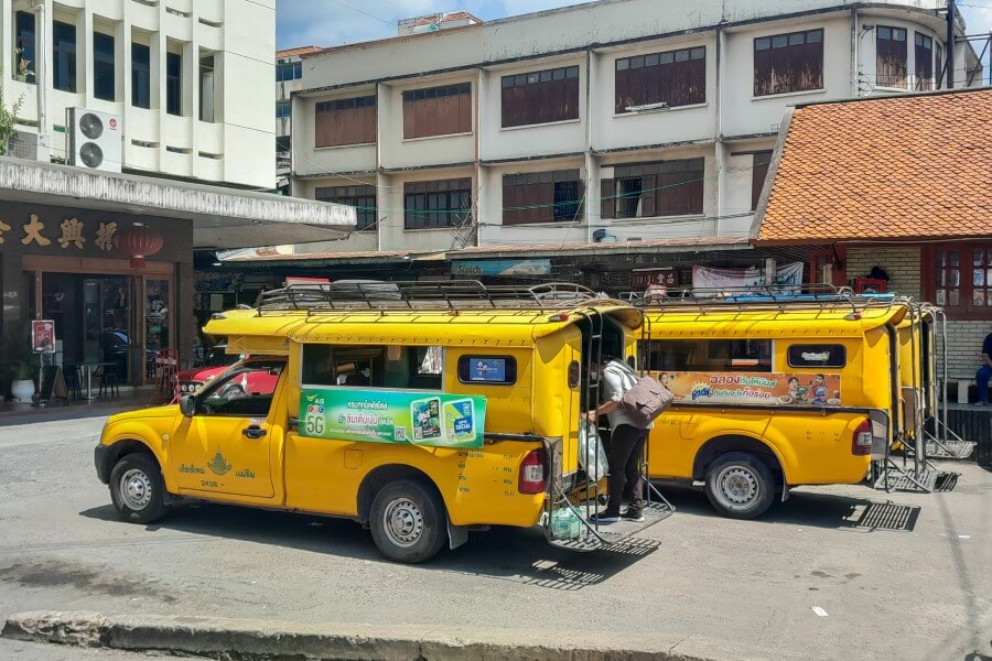 a woman getting into a yellow songthaew in chiang mai thailand
