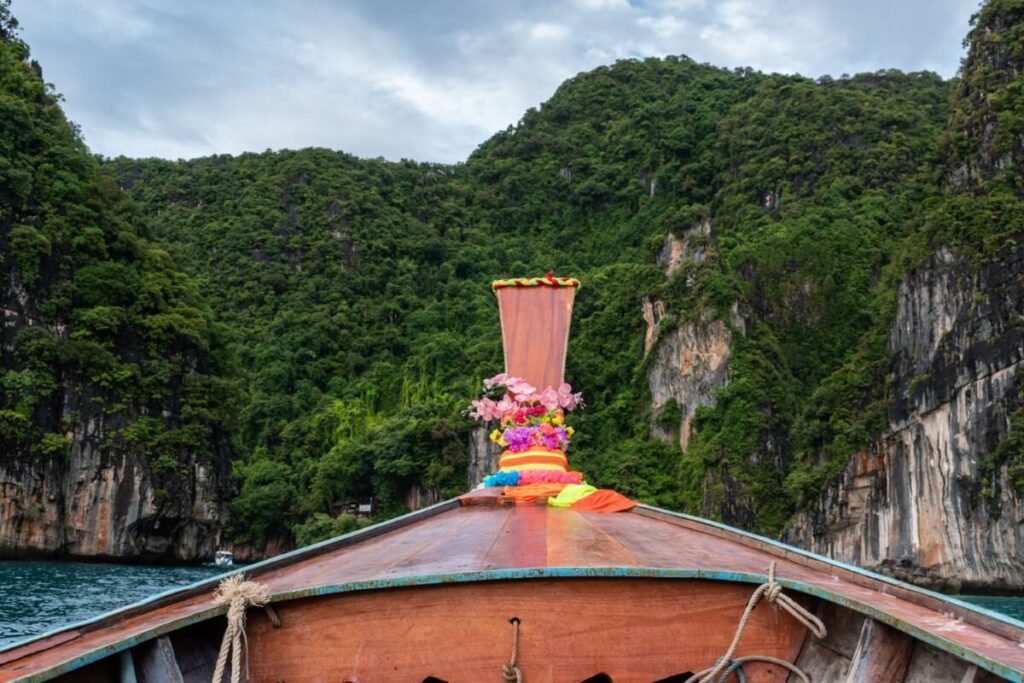 a longtail boat decorated with colorful flowers with karst cliffs in the backdrop phi phi islands tour from krabi