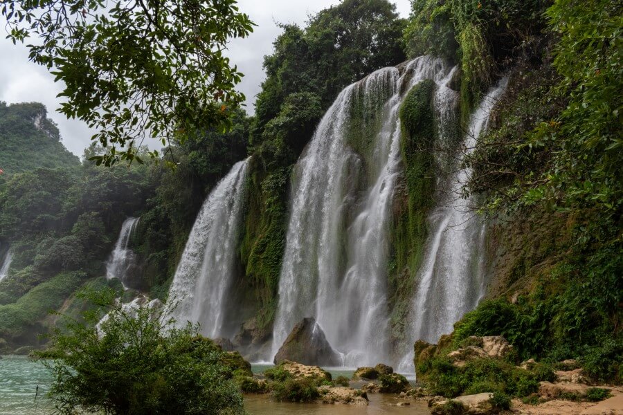 ban gioc waterfall gushing from a cliff surrounded by lush vegetation