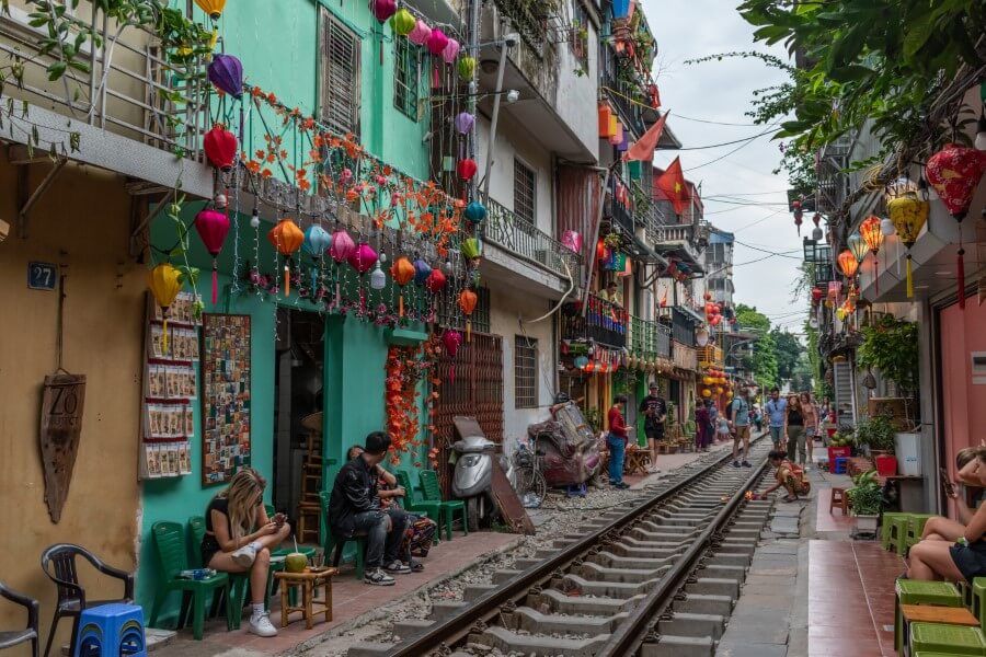 people sitting along a train track at hanoi train street