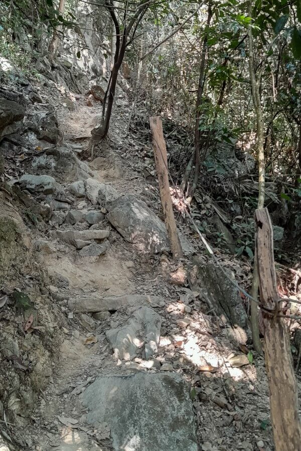 a rocky hiking trail with steel wire handrails on the side
