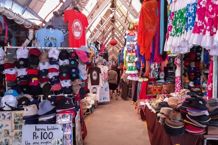 a small market with rows of stalls selling clothes, hats, and handbags