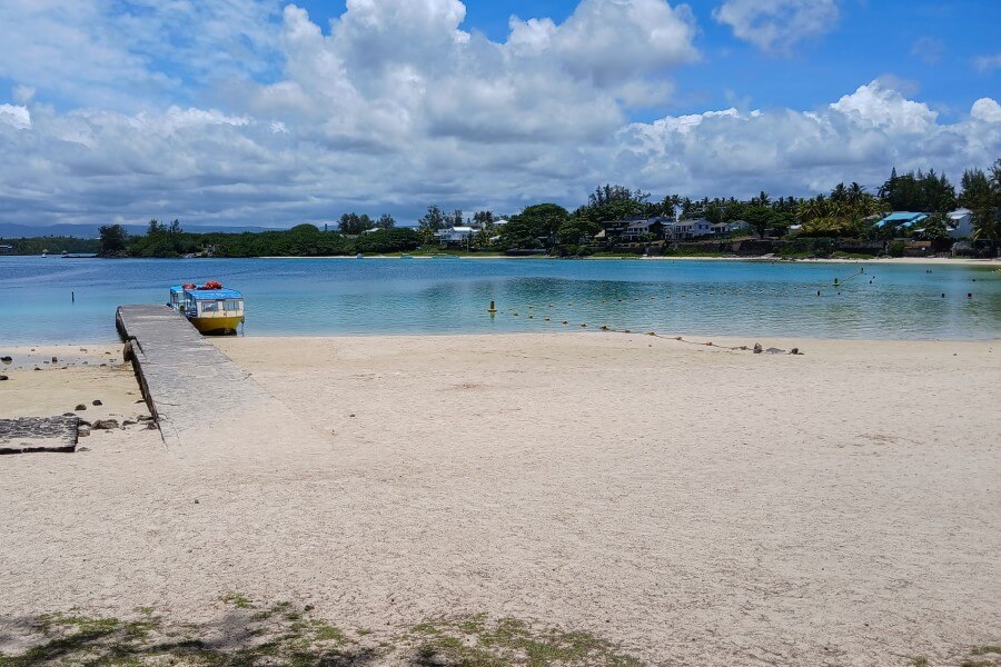 a jetty on a white sand beach at blue bay mauritius