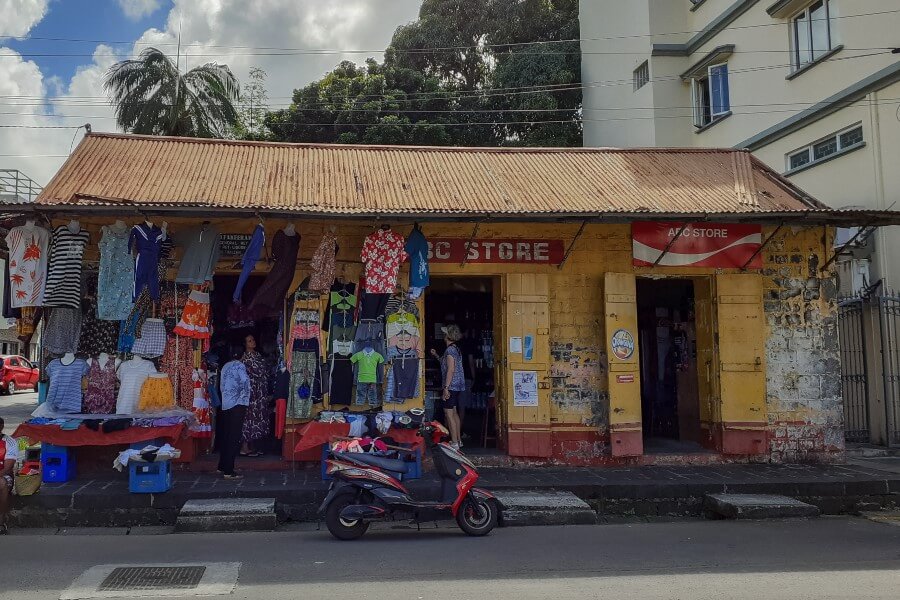 people walking in front of an old building painted in yellow and red