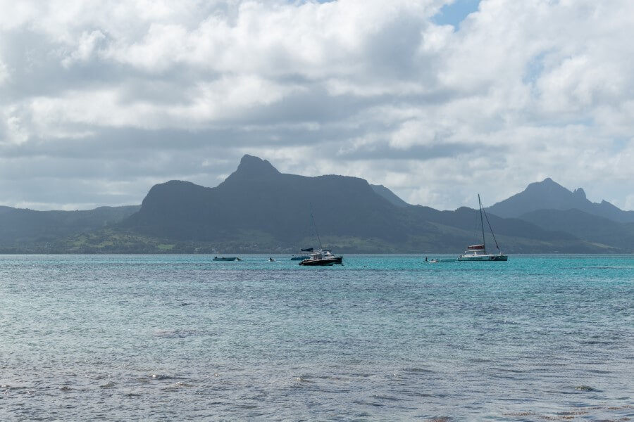 the ocean dotted with boats with a mountain in the background