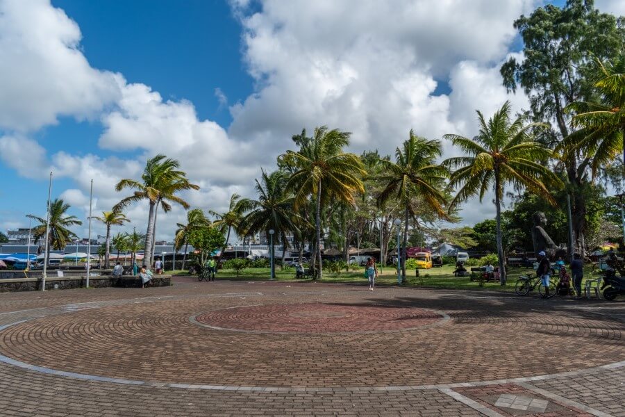 a cobblestoned plaza surrounded by palm trees at mahebourg waterfront